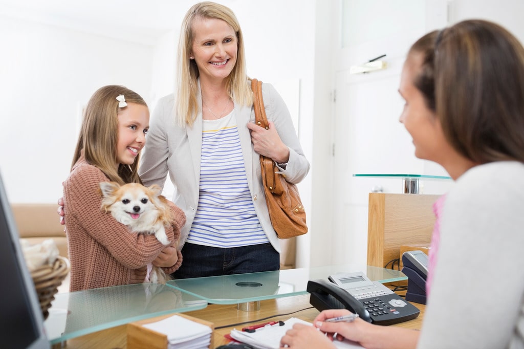 Family with dog happily checking in at pet care center using RunLoyal app