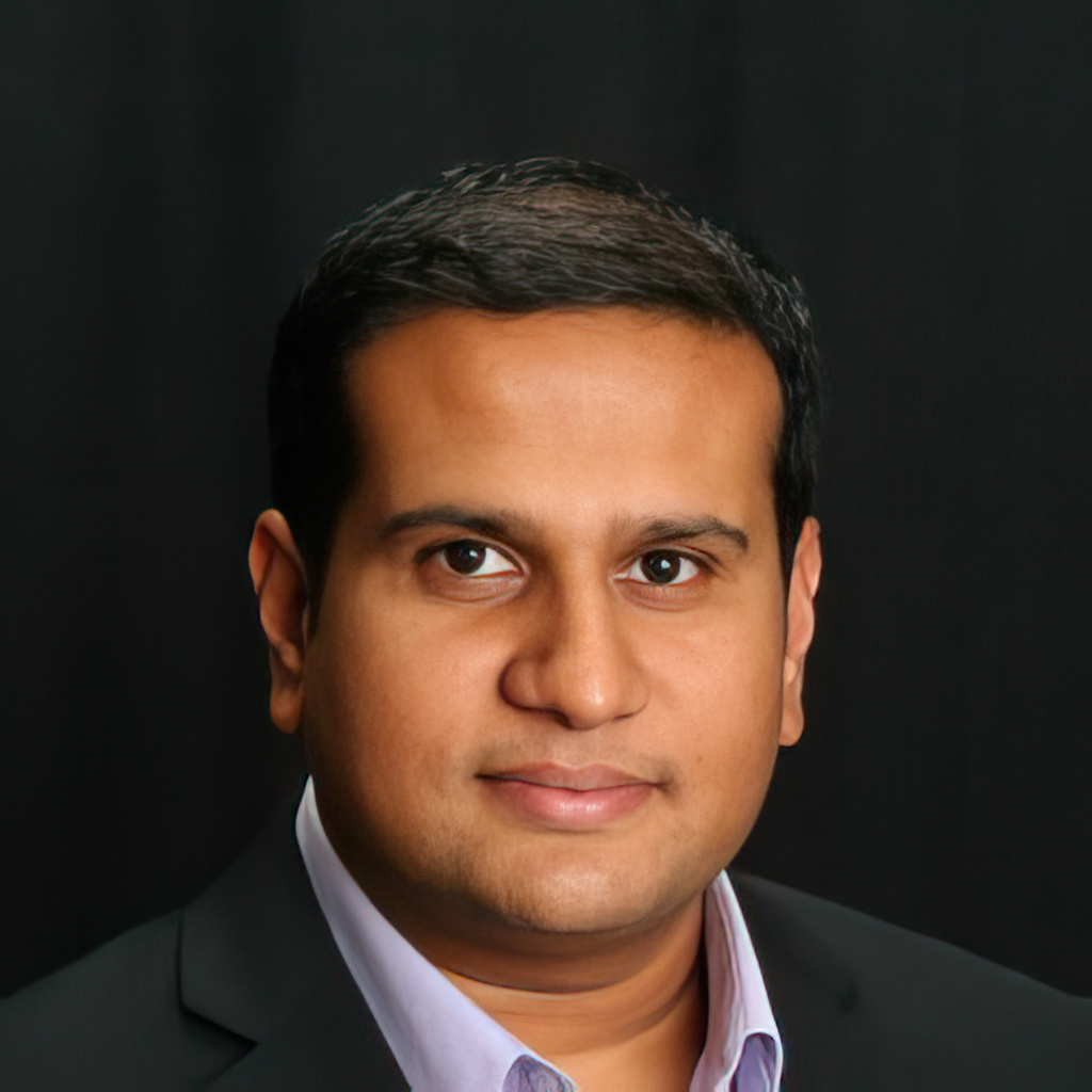 A close-up portrait of a man with short dark hair, wearing a suit jacket and a light-colored shirt, standing against a dark background, reminiscent of someone who might be an expert in pet care.